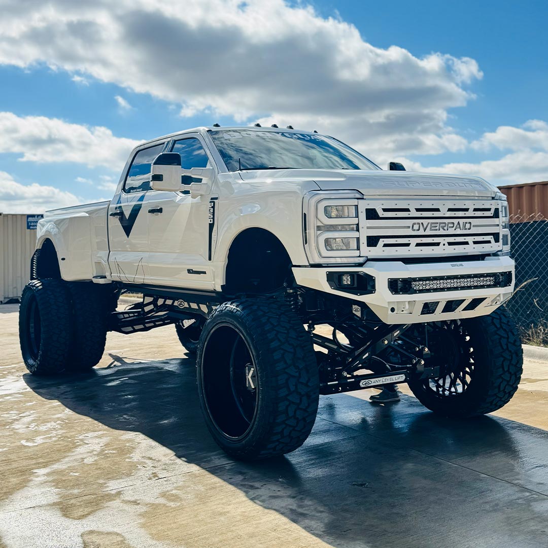 clean shiny lifted white truck under blue sky and clouds
