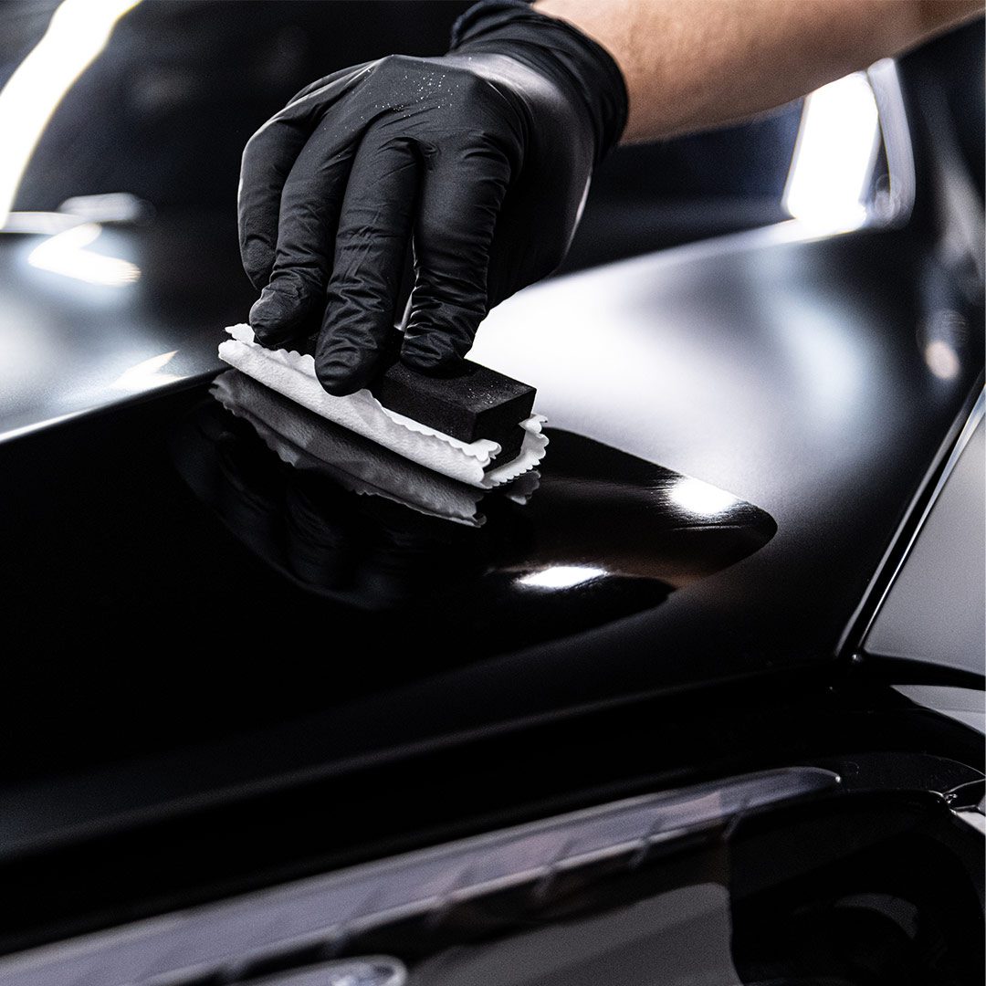 man applying ceramic coating polic on car closeup