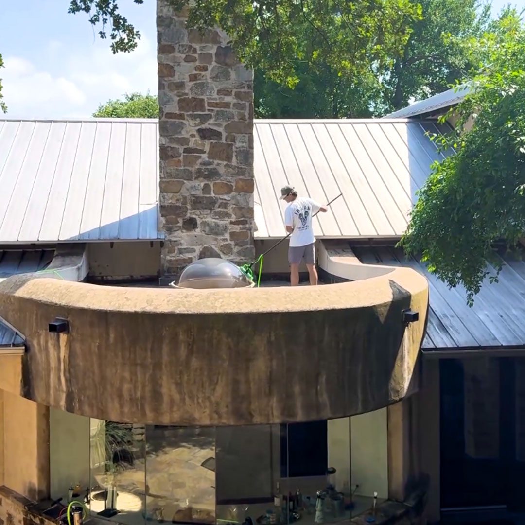 man washing skylight on roof