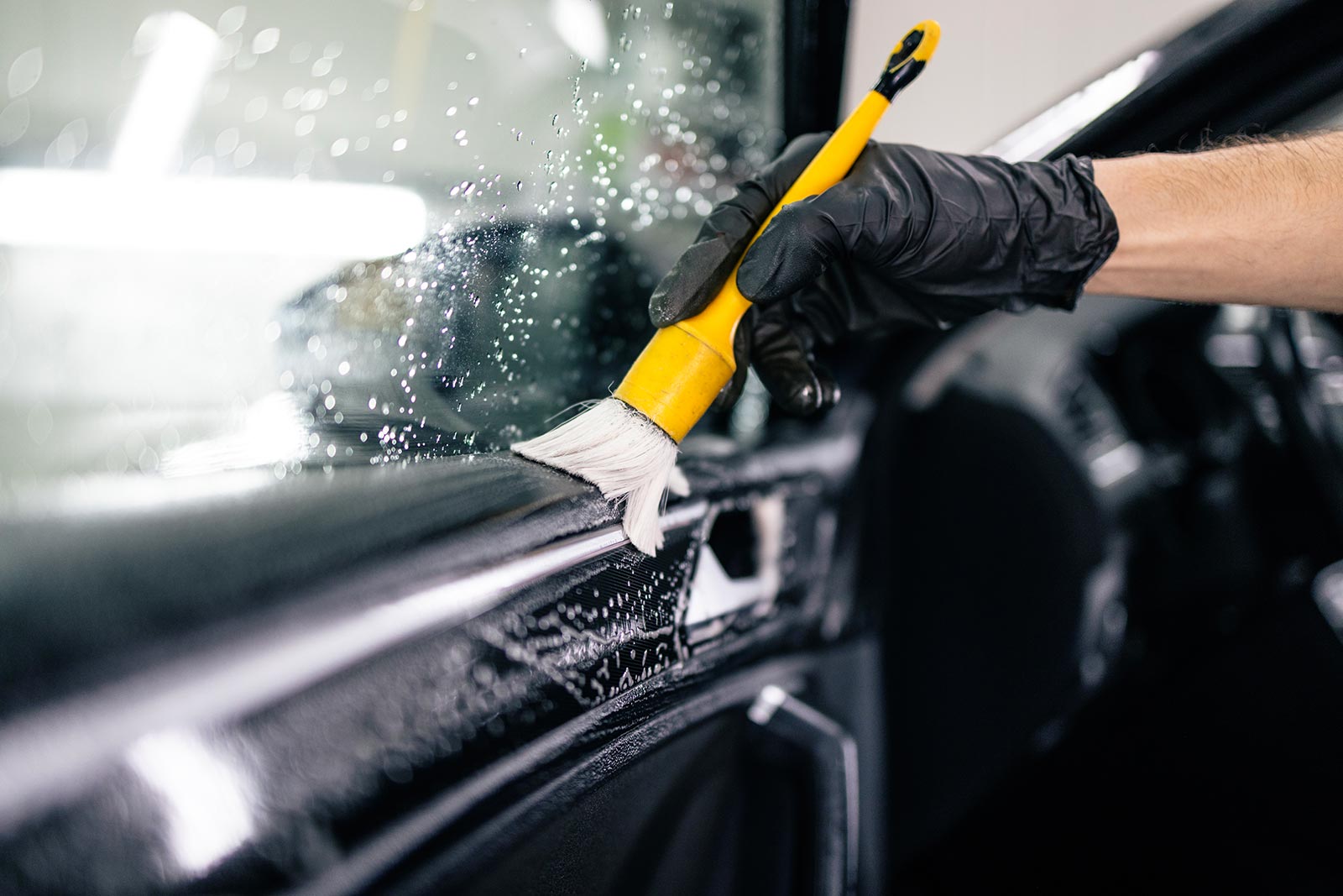 person cleaning inside car door with brush