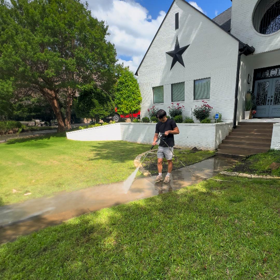 person power washing front of house walkway