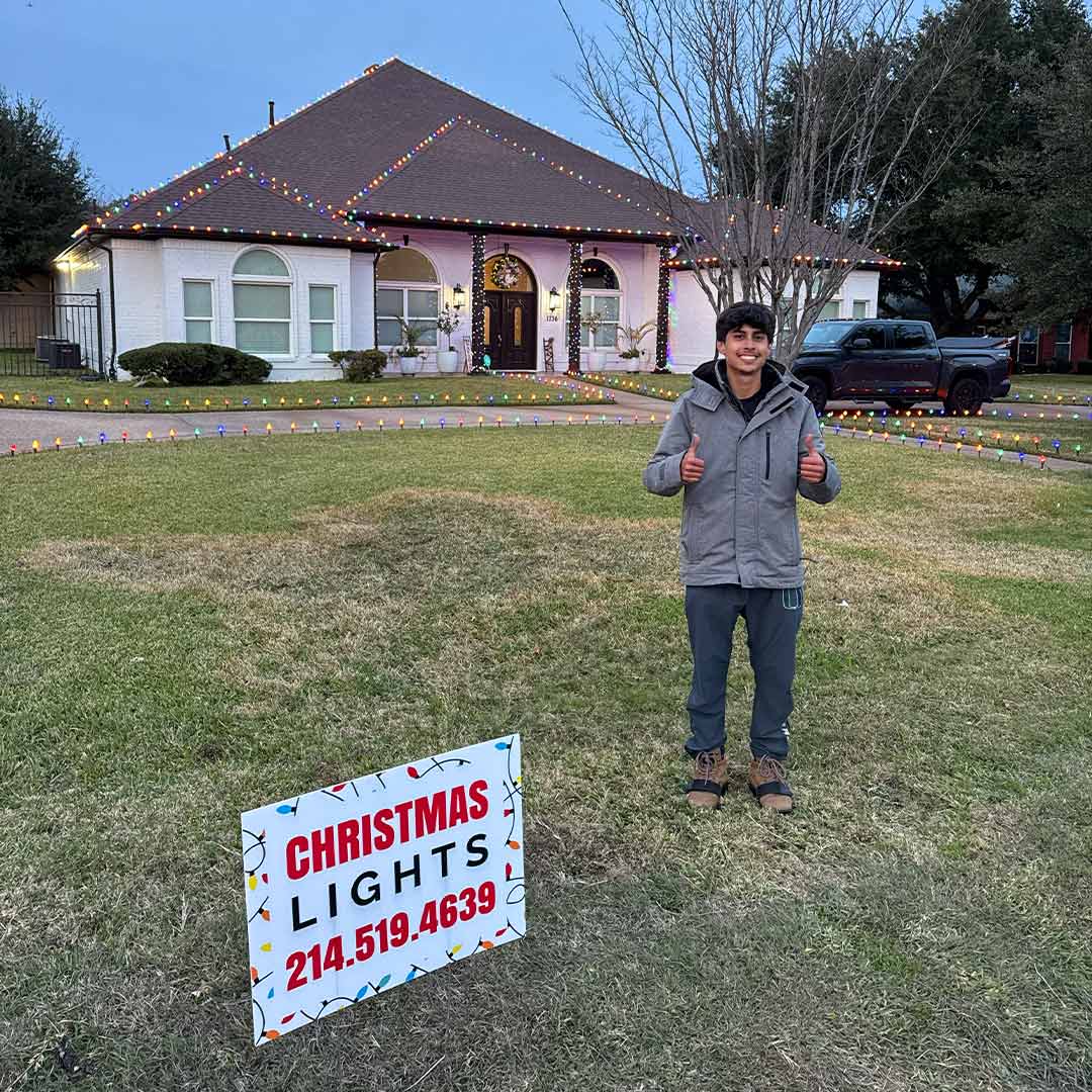 Technician standing in front of a completed Christmas light installation on a luxury home in Dallas-Fort Worth, TX