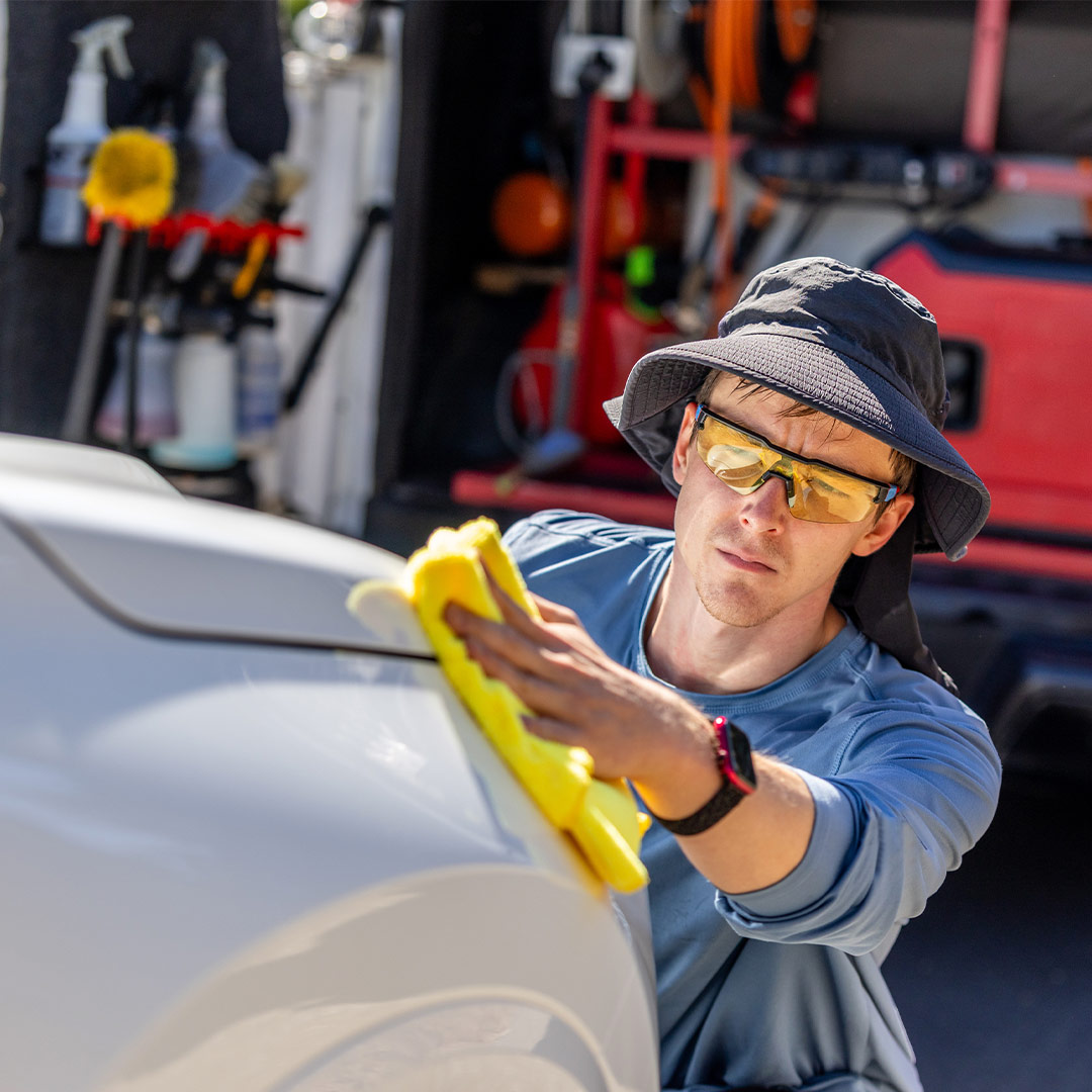 Professional exterior car detailing technician wiping vehicle paint in Fort Worth TX